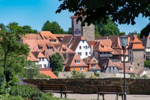 Ein Fluss mit T, die Tauber, fließt durch das Tal unterhalb der historischen Altstadt von Rothenburg ob der Tauber.