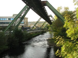 Deutscher Fluss mit W: Die Schwebebahn in Wuppertal über dem Fluss Wupper